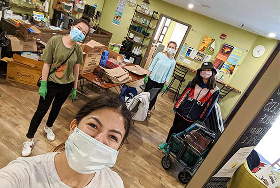 UC San Diego students inside the Basic Needs space on campus; groceries and packaged food items on shelves and tables in the background