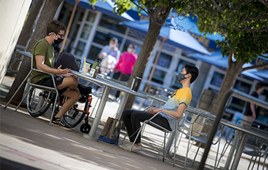Photo of masked UC San Diego students sitting at a distance from one another, outside in Price Center Plaza - photo by Erik Jepsen, UC San Diego