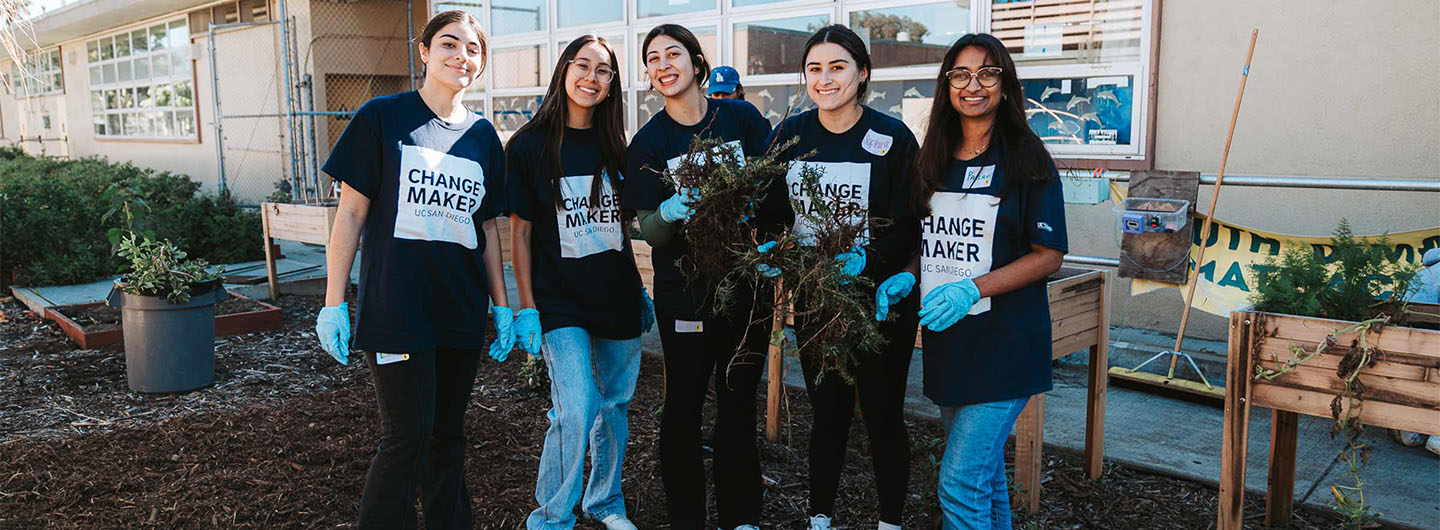 UC San Diego students pose in their Changemaker shirts, in a garden they are replanting